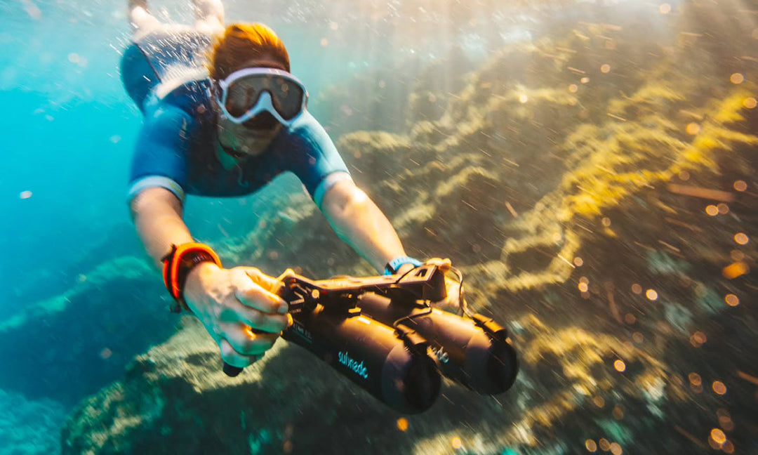 Snorkeler using a Waydoo Subnado underwater scooter above a coral reef